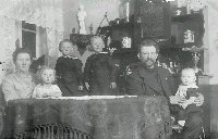 Bedstefar og bedstemor, Jens og Marie, med børnene Alma, Peter, Michael og Valborg i stuen på Blikshøj omkring 1920.